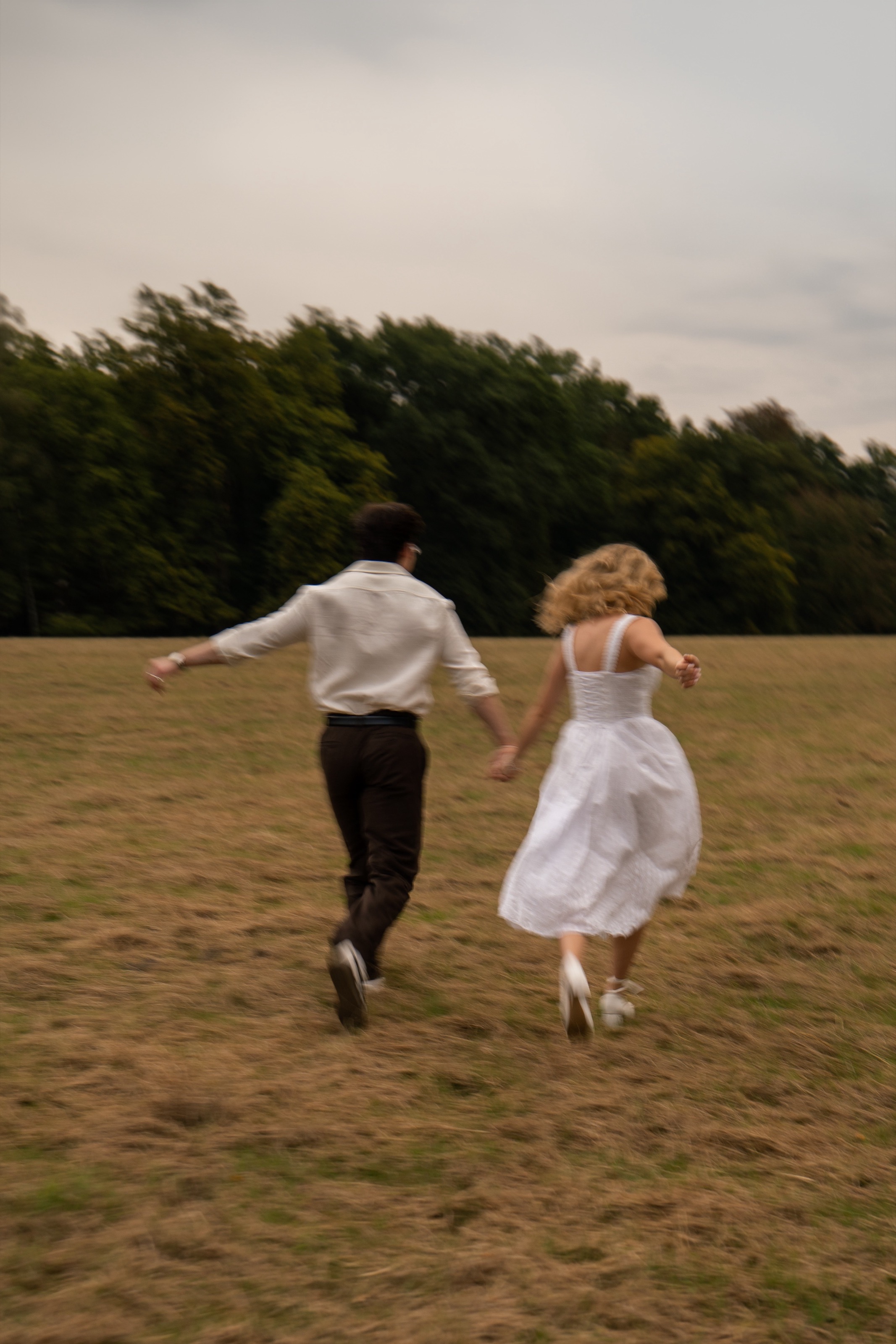 Laughing couple running hand in hand across a meadow